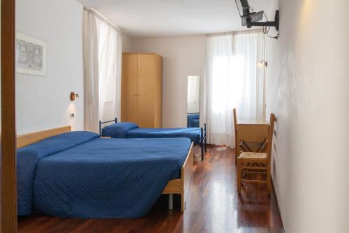 a bedroom with two beds with blue sheets and a window at Arco del vento in Assisi