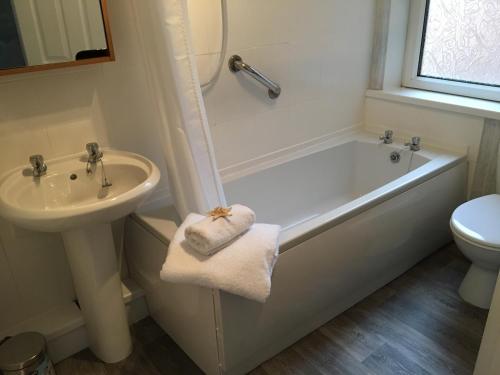 a bathroom with a tub and a sink and a toilet at The Mules in Newbiggin-by-the-Sea