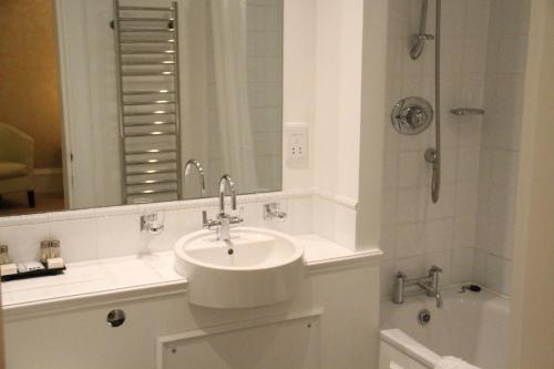 a white bathroom with a sink and a shower at Annandale Arms Hotel in Moffat