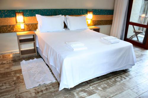 a bedroom with a large bed with white sheets and pillows at Ilha Deck Hotel in Ilhabela
