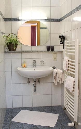 a white bathroom with a sink and a mirror at Appartementhaus Safferstetten in Bad Füssing