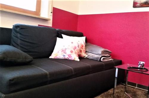 a black couch with pillows on a red wall at Ferienwohnung-4you in Sigmarszell