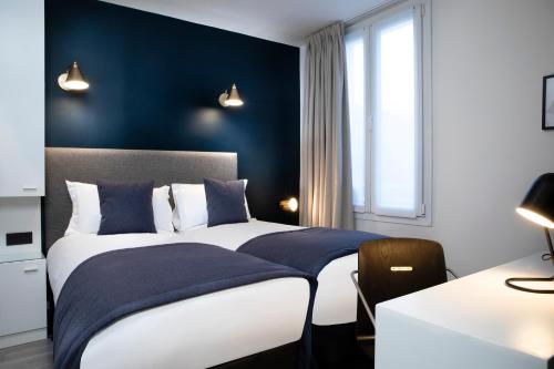 a bedroom with a bed with a blue wall at Hôtel Brady in Paris