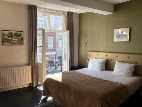 a bedroom with a bed and a large window at Boutique Hotel Grote Gracht in Maastricht