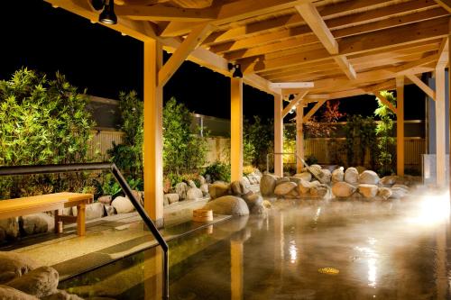 una piscina in un cortile posteriore di notte con un padiglione di Air Terminal Hotel a Chitose