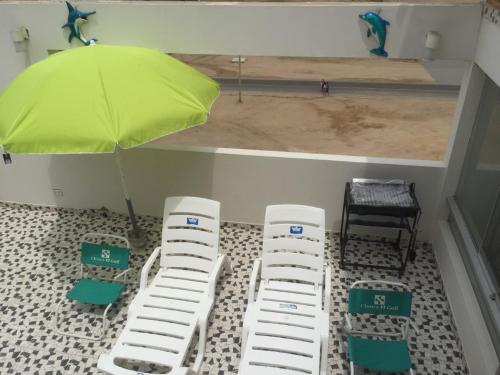 a room with three chairs and a green umbrella at Departamentos Playa San Bartolo in San Bartolo