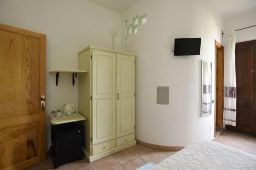 a bedroom with a bed and a cabinet and a television at Baja Azzurra in Bari Sardo