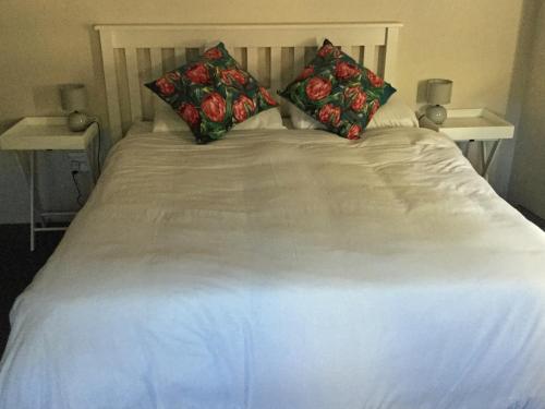 a large white bed with two pillows on it at Stylish Country Cottage, Solar panelled in Knysna in Knysna