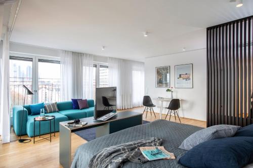 a living room with a blue couch and a desk at THE FLAG Oskar M. in Frankfurt/Main