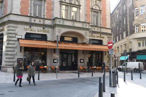 two people walking down a street in front of a building at Estilo Fashion Hotel Budapest in Budapest