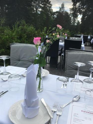 a table with a vase with a pink flower in it at Hotell Plevnagården in Malmköping