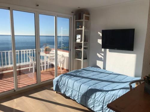 a bedroom with a balcony with a bed and a television at Espectacular apartamento cerca de Barcelona con free wifi in Canet de Mar