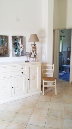 a white dresser with a lamp and a chair at Casa Bithia in Chia