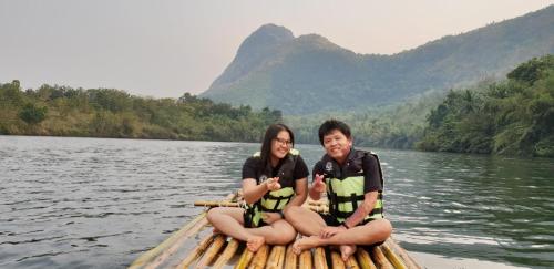 a man and woman sitting on a boat on the water at Baan Krupong in Ban Tha Thong Mon