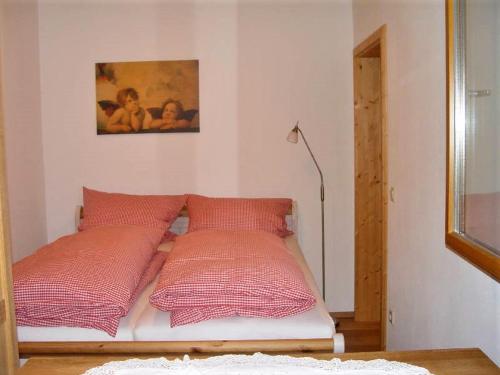 a bed with four red pillows in a room at Haus Weichart in Sulzburg