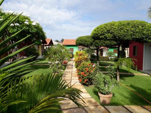 a garden with plants and trees and a house at Chalés do Otto e Karine in Canoa Quebrada