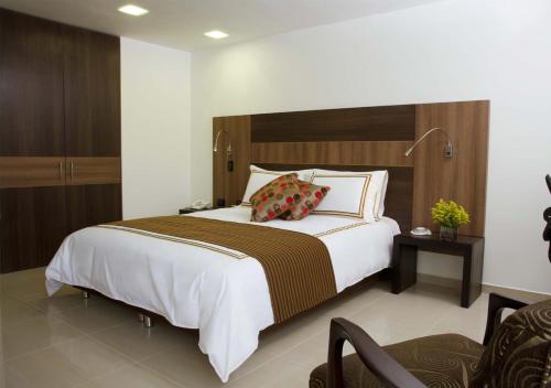 a bedroom with a large bed with a wooden headboard at San Simon Hotel Pereira in Pereira