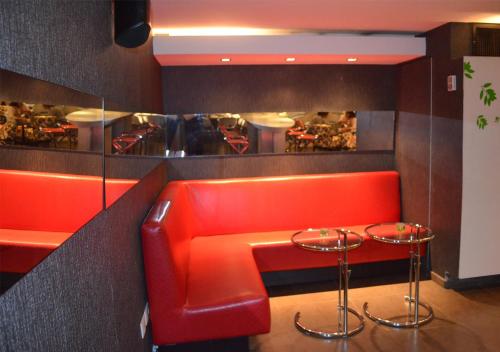 a red bench in a restaurant with two stools at San Simon Hotel Pereira By Soratama in Pereira