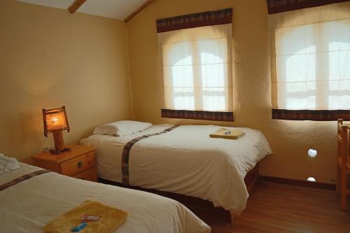 a hotel room with two beds and two windows at Ecolodge Copacabana in Copacabana