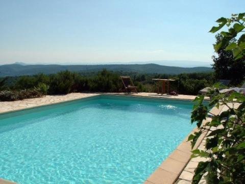une grande piscine bleue avec des montagnes en arrière-plan dans l'établissement Le Mas de Fournery, à Villeuneuve-de-Berg