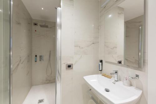 a white bathroom with a sink and a shower at Floris Hotel in Rome