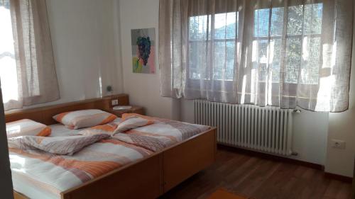 a bed in a bedroom with two windows at Georg Barbieri "Bindergor-Hof" in Terlano