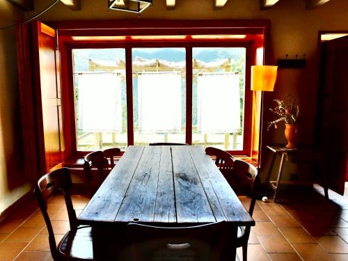 a wooden table with chairs in a room with windows at El Serrat Turisme Rural in Planoles