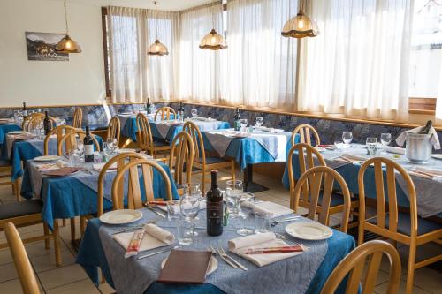 uma sala de jantar com mesas e cadeiras azuis em Hotel Montana em Fai della Paganella
