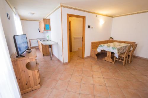a room with a table and a kitchen with a television at Hotel & Residence Montana in Fai della Paganella