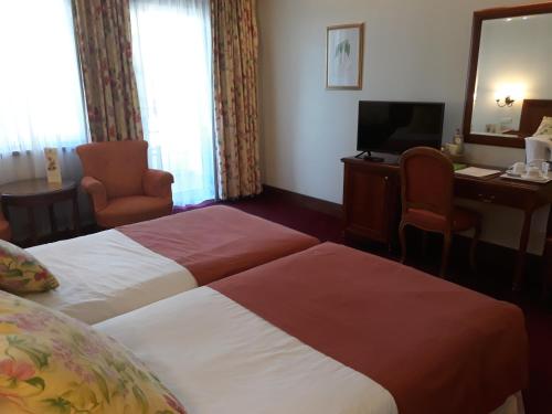 a hotel room with two beds and a desk and a television at Quinta Da Penha De Franca in Funchal