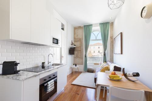 a kitchen with white cabinets and a table with bananas on it at Host Wise - Charming Flat with Netflix - River View in Porto