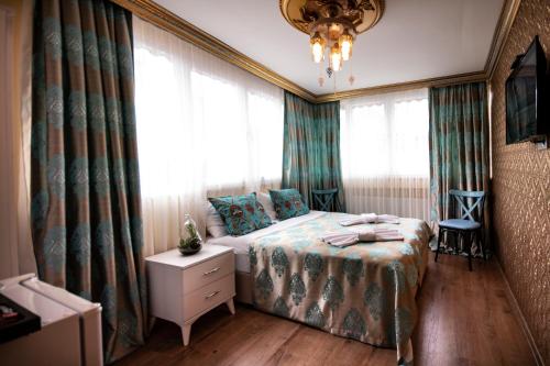 a bedroom with a bed and curtains and a chandelier at Paris Garden Hotel Istanbul in Istanbul