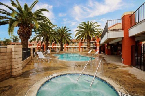 a swimming pool with palm trees and a building at Days Inn by Wyndham Hemet in Hemet
