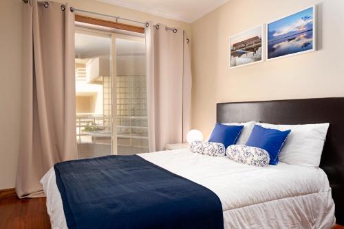 una camera da letto con un grande letto con cuscini blu e bianchi di BARRAMARES 1 a Furadouro