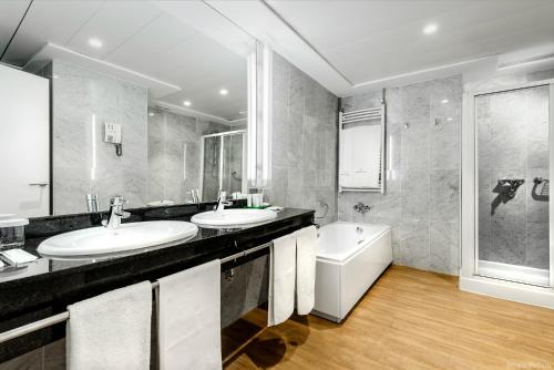 a bathroom with two sinks and a tub at Hotel Tres Reyes Pamplona in Pamplona