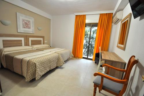 a bedroom with two beds and a desk and a window at Hotel Goya in Almuñécar