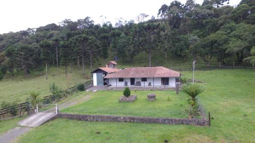 una pequeña casa blanca en un campo con una colina en Sitio Itaimbé - Casa e Chalé - Morro da Igreja, en Urubici