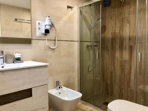 uma casa de banho com um chuveiro, um WC e um lavatório. em Apartamentos Apolo 16 em Calpe