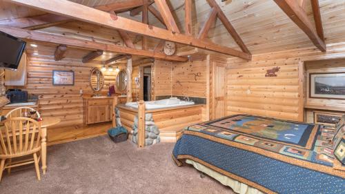 a log cabin bedroom with a bed and a tub at Upper Canyon Inn & Cabins in Ruidoso