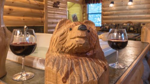 a bear statue sitting on a counter with two glasses of wine at Upper Canyon Inn & Cabins in Ruidoso