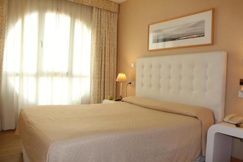 1 dormitorio con cama blanca y ventana en Hotel Bouza, en Ribadeo