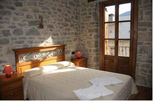 a bedroom with a bed and a stone wall at Casa Felices in Broto