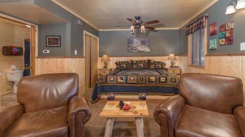 a bedroom with a bed and two chairs and a table at Upper Canyon Inn & Cabins in Ruidoso