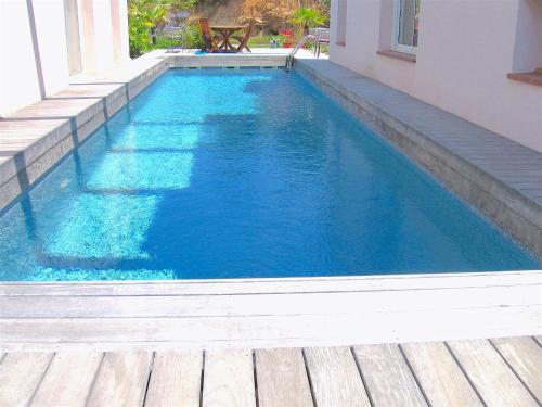 une piscine d'eau bleue et une terrasse en bois dans l'établissement Villa avec piscine et belle vue mer proche des plages et commerces, à Porticcio