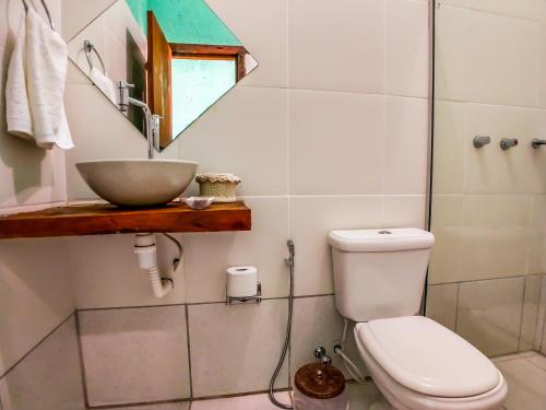 La salle de bains est pourvue d'un lavabo, de toilettes et d'un miroir. dans l'établissement Pousada Zimbauê, à Itaúnas