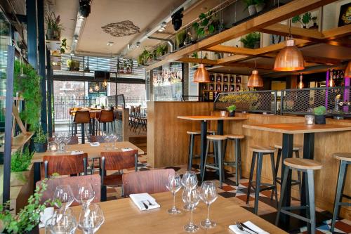 a restaurant with wooden tables and chairs and wine glasses at Hotel De Schout in Denekamp