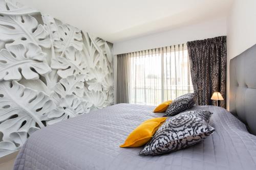 une chambre avec un grand lit avec des oreillers jaunes dans l'établissement 2-Br apartment 2 minutes from the beach parking, à Cannes