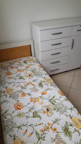 1 dormitorio con 1 cama con colcha de flores en Apartamento Orquídea en Campos dos Goytacazes