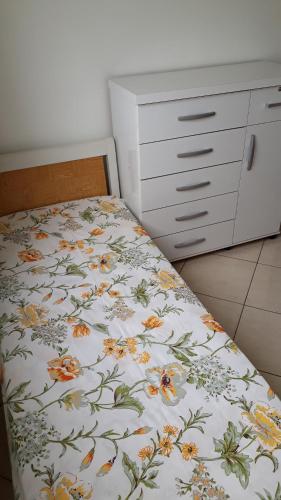 a bedroom with a bed with a floral bedspread at Apartamento Orquídea in Campos dos Goytacazes