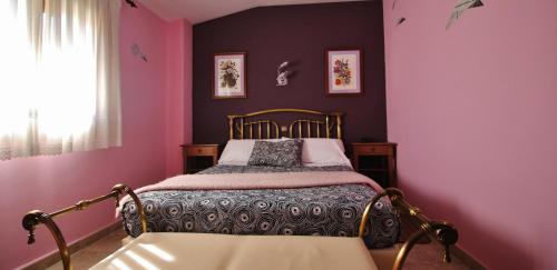a bedroom with a bed with pink walls and a window at Posada Del Camino Real in Torrelaguna